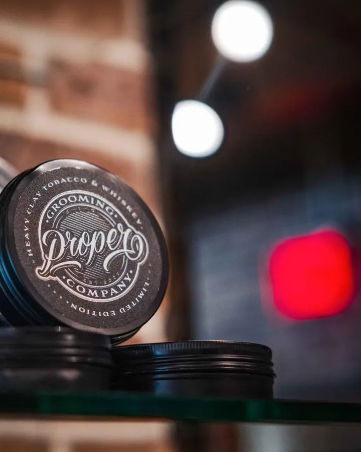 A tin of grooming product on a shelf, with the shop’s lights behind it