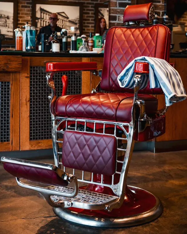 A red leather barber chair with a towel over the arm