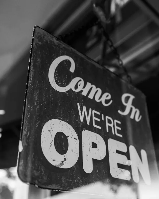 A “Come in, we’re open” sign in black and white