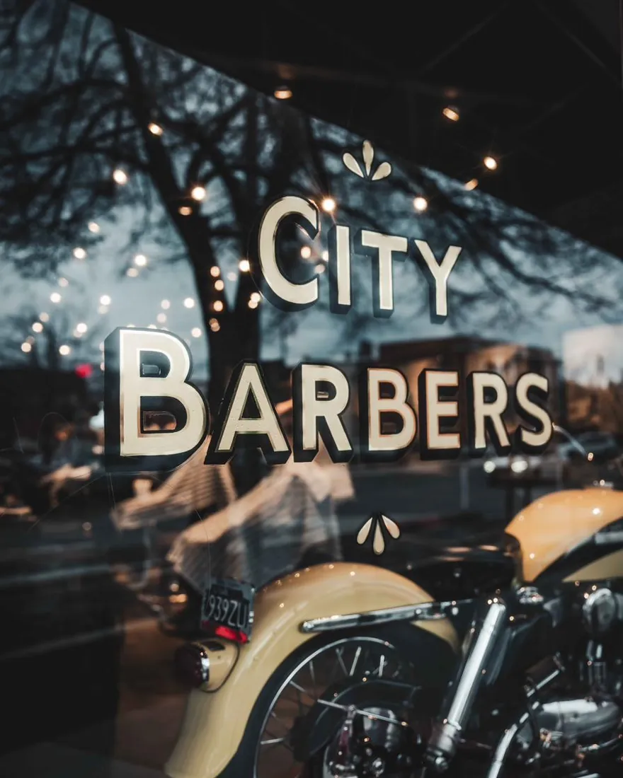 Gold City Barbers lettering on the front window at night