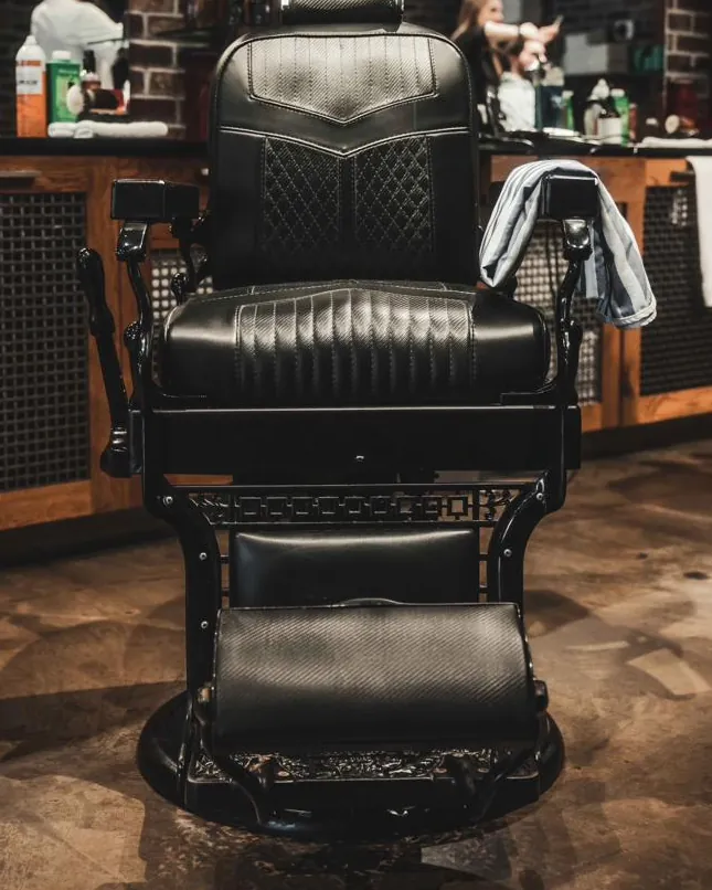 A black leather barber chair under string lights