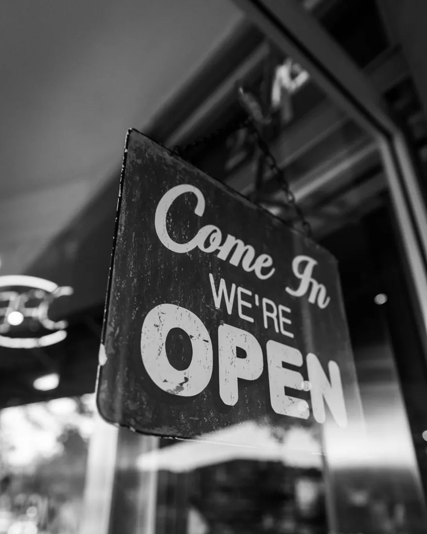 A black-and-white photo of a “Come in, we’re open” sign