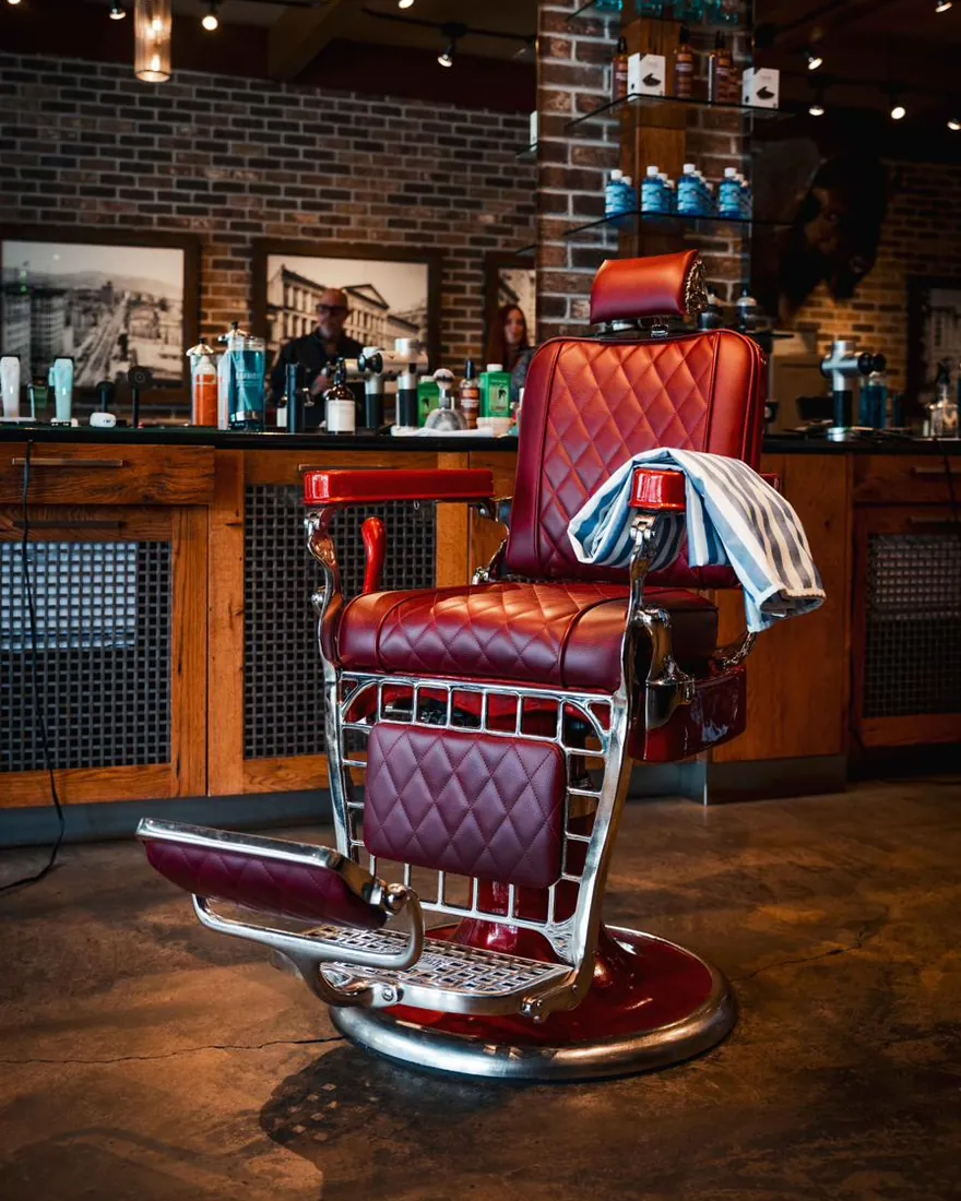 A red leather barber chair with a towel draped over the arm