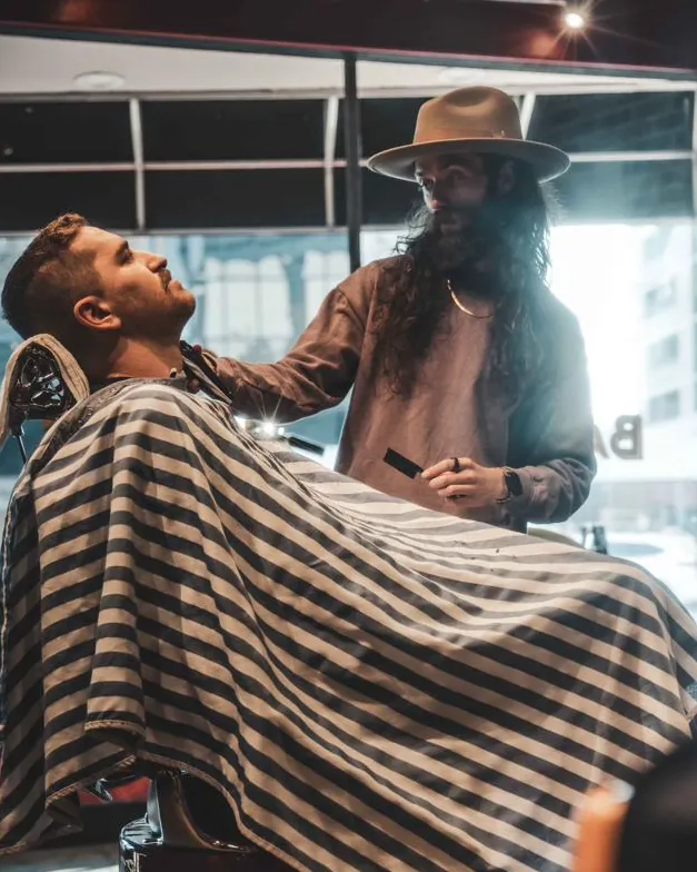 A barber in a wide-brimmed hat working by the front window