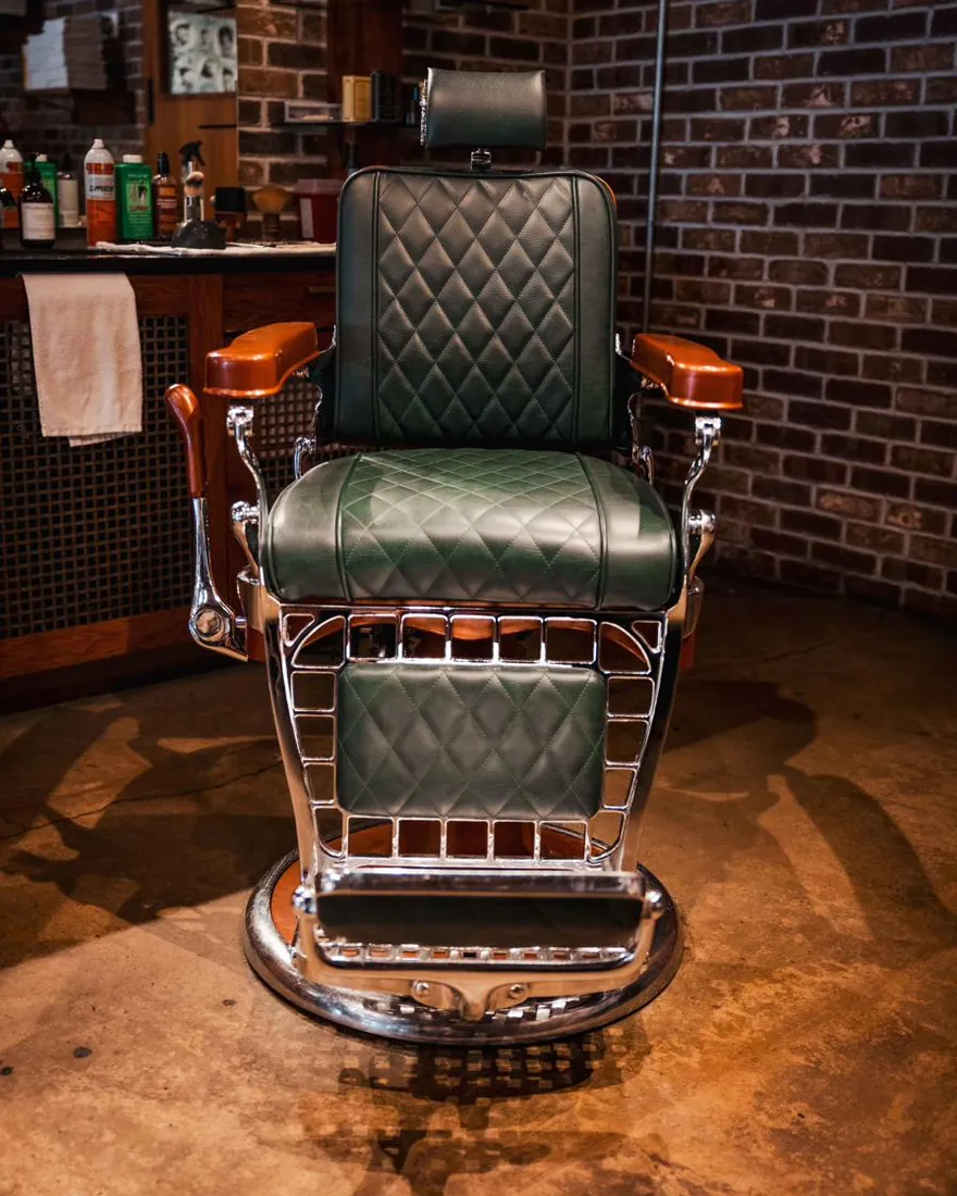 A green leather barber chair on the shop floor