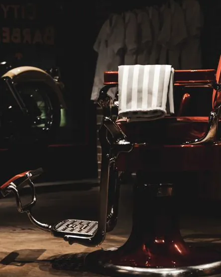 A red barber chair lit by a single light in the darkened shop