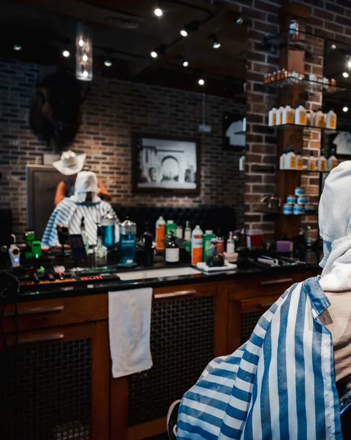 A client with a towel wrapped over his head at his barber chair