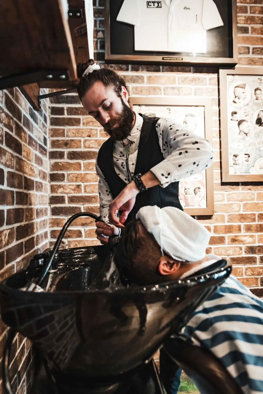 A barber wrapping a client in a hot towel at City Barbers